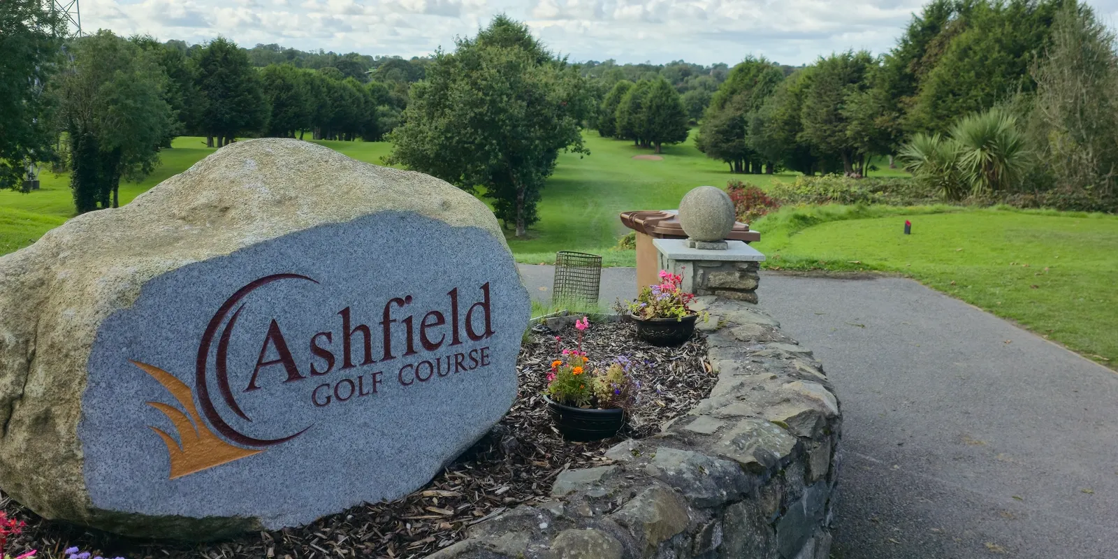 The engraved Ashfield Golf Course entrance stone, with the course beyond